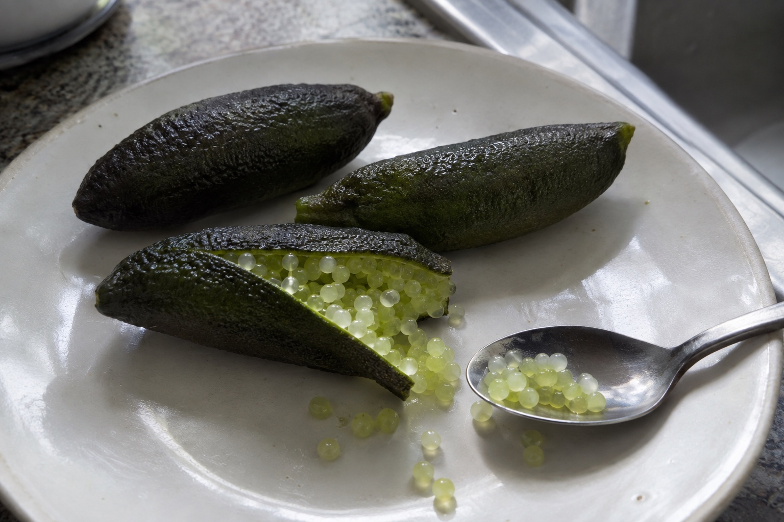 Des citrons caviar vert foncé ouverts, avec leurs petites billes de pulpe vert pâle.