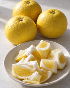 Illustration de fruits de Hyuganatsu jaunes et de quartiers conservant leur albédo blanc comestible